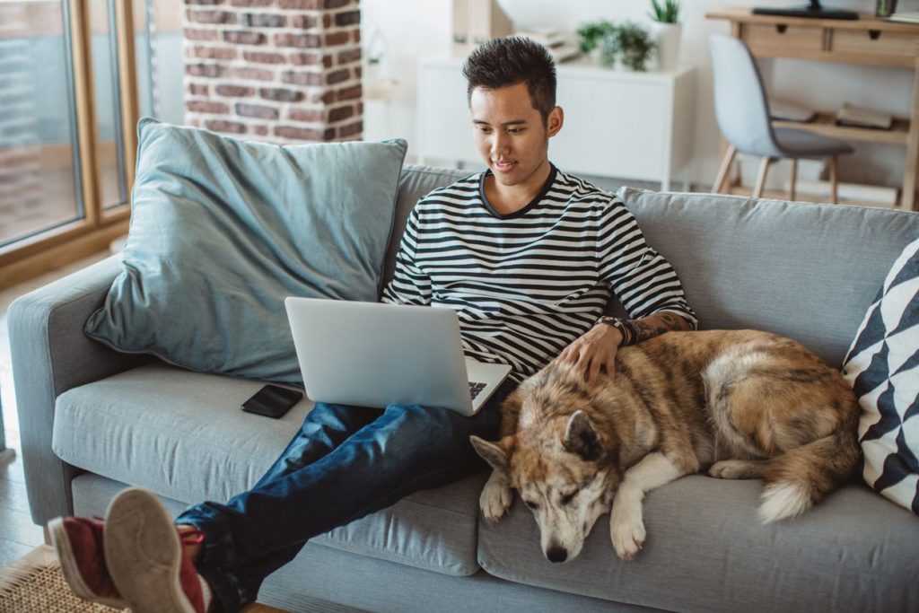 Young man sitting on sofa with his dog.