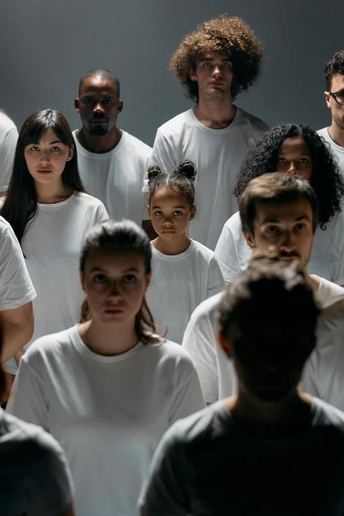A diverse group of people of different ages and racial backgrounds stand together wearing white shirts, representing racial identity and diversity.