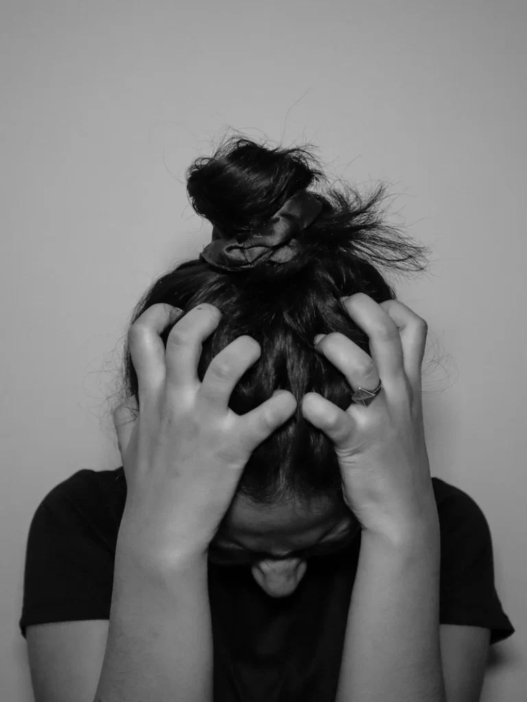 A person grips their head with both hands, appearing overwhelmed and distressed, representing symptoms of a panic disorder.